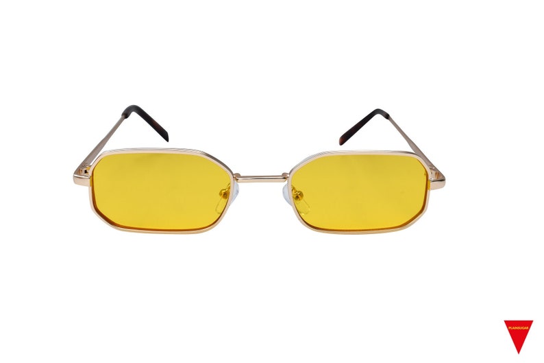 May include: Gold-rimmed sunglasses with yellow lenses. The sunglasses have a rectangular shape.