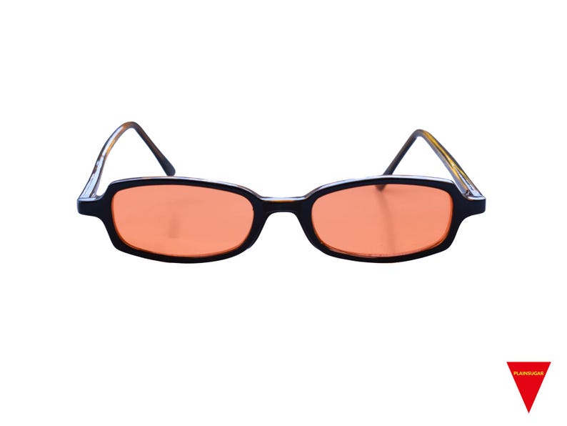 May include: Rectangular sunglasses featuring black frames and orange-tinted lenses. The temples have a tortoiseshell pattern on the inner side. A small red triangle logo with the text "PLAINSUGAR" is visible in the bottom right corner.