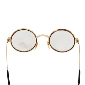 May include: Gold-rimmed round eyeglasses with clear lenses and black temple arms.