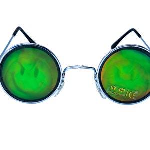May include: Round, silver-framed sunglasses with green, iridescent lenses. The lenses have a subtle smiley face pattern. The right lens has the text "UV 400 PROTECTION CE" printed on it.