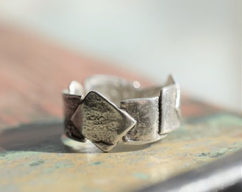 May include: A silver ring with a geometric design. The ring is made of multiple connected diamond shapes.