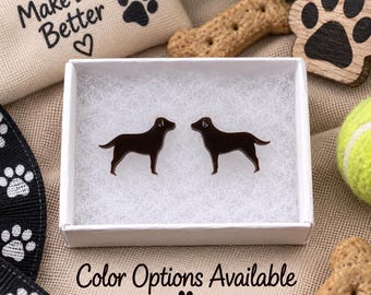 May include: A pair of dark brown dog-shaped stud earrings resting on white padding inside a small white box. The earrings are shaped like Labrador retrievers in profile, featuring a smooth, glossy finish and a simple, minimalist silhouette.