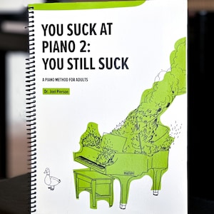 May include: A white book with a green spine and a black and white illustration of a piano with a duck on the cover. The title of the book is "You Suck at Piano 2: You Still Suck" and the subtitle is "A Piano Method for Adults". The author is Dr. Joel Pierson.