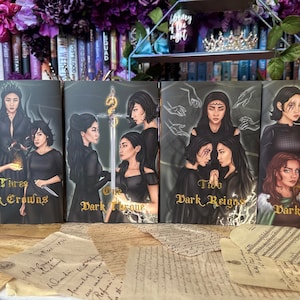 May include: Four fantasy novel book covers with dark backgrounds and gold lettering. The titles are "Three Dark Crowns", "One Dark Throne", "Two Dark Reigns", and "The Dark Palace".
