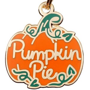 May include: Gold-colored pumpkin-shaped dog tag with green leaves and the text "Pumpkin Pie" in gold lettering.