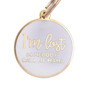 May include: White metal dog tag with a gold ring and the text "I'm lost, Somebody call my mama" in gold lettering.