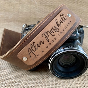 May include: A brown leather camera strap with a personalized nameplate that reads "Allen Marshall Sun & Moon Imagery".