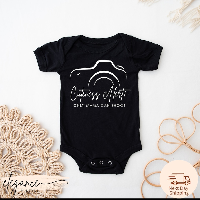 a baby bodysuit with a camera logo on it