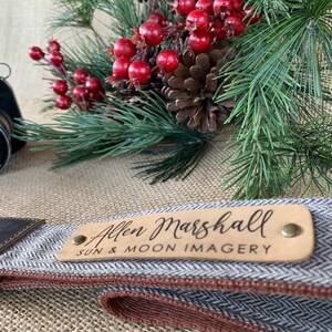 May include: A brown leather and gray tweed camera strap with a brown leather patch that says "Allen Marshall Sun & Moon Imagery".