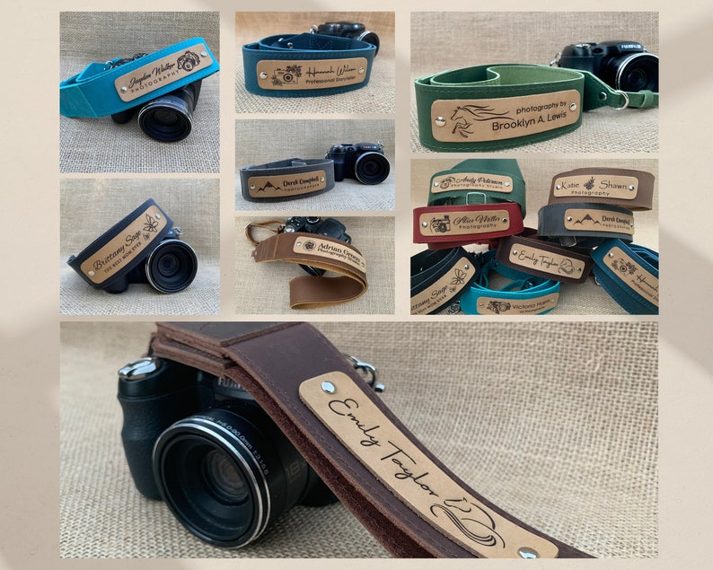 May include: A collection of personalized camera straps with various colors and designs. Each strap features a wooden tag with a name or business name engraved on it. The straps are made of leather and have adjustable lengths.