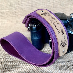 May include: Purple leather camera strap with a brown leather patch that says "AVERY PEARSON photographer" with a floral design.
