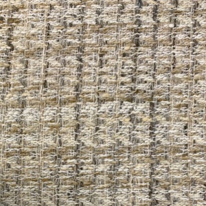 Könnte beinhalten: Nahaufnahme eines beigefarbenen Gewebes mit einem dezenten Streifenmuster. Der Stoff hat eine strukturierte, leicht raue Oberfläche.