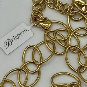 May include: A gold-toned chain necklace with a heart-shaped charm that says "Brighton." The chain is made of interlocking oval links.