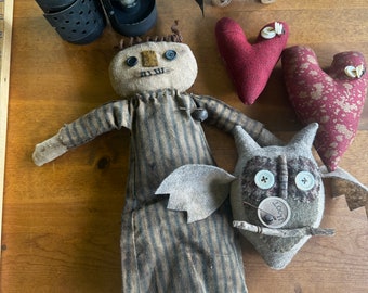 May include: A collection of handmade primitive folk art items, including a rag doll, a pig, two lanterns, and two hearts. The doll is wearing a striped dress and has a button nose and eyes. The pig is made of felt and has a button nose and eyes. The lanterns are made of metal and have a distressed finish. The hearts are made of fabric and have a floral pattern.
