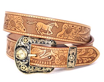 May include: A tan leather belt with a detailed floral and horse design. The belt features a decorative buckle with gold and black accents. The belt is a western-style accessory.