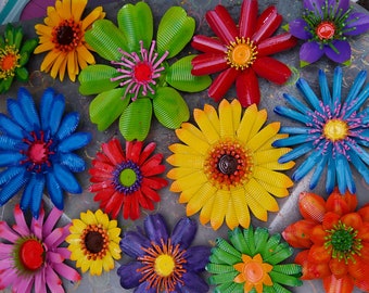 May include: A collection of 12 colourful metal flowers with various designs and colours, including red, yellow, blue, green, and purple. The flowers are made from recycled materials and have a rustic, handmade look.