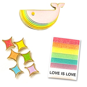 Könnte beinhalten: Satz mit sechs Regenbogen-Emaille-Pins mit einem Wal, Sternen und einem Regenbogen mit dem Text "LOVE IS LOVE".