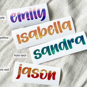 May include: Four rectangular adhesive labels featuring custom names in a bold, rounded font. The labels display holographic color gradients: 'emily' in purple, 'isabella' in yellow, 'sandra' in teal, and 'jason' in red, each labeled with its color.