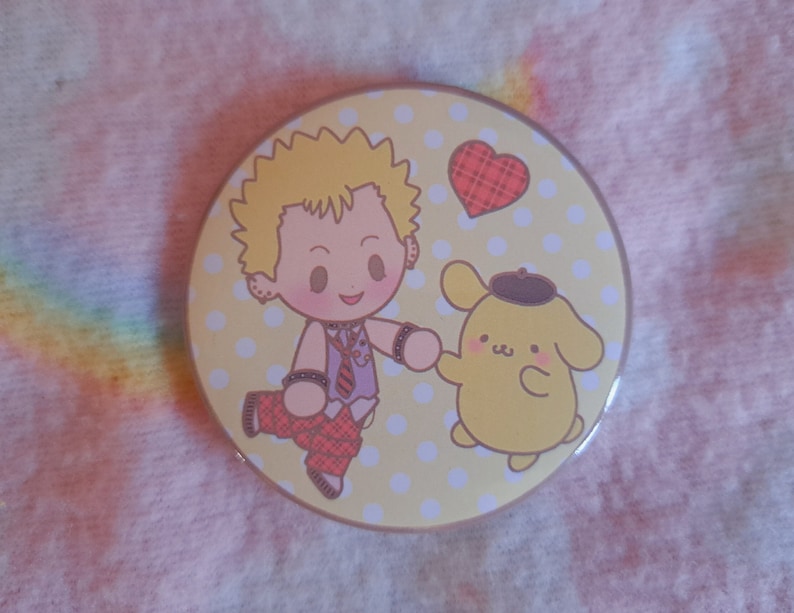 May include: A circular badge with a cartoon illustration on a yellow background with white polka dots. The design features a character with blonde hair and a dog-like character holding hands, with a red heart.
