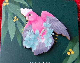 May include: A pink Galah bird wooden pin with blue and green foliage on a green background. The card reads "Galah Wooden Pin".