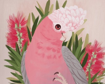 May include: A pink and gray cockatoo bird with a pink crest perched on a branch of green leaves and pink flowers.