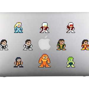 Puede incluir: Un portátil plateado con diez pegatinas de personajes pixelados. Los personajes están en varias poses y colores, incluyendo rojo, azul, verde, amarillo y naranja.