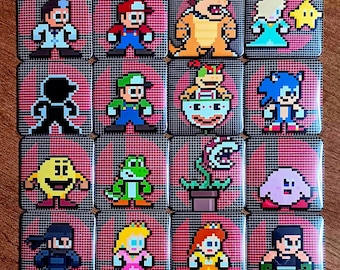 May include: A collection of sixteen square pin-back badges arranged in a four-by-four grid. Each badge features a pixel art character from various video games set against a red circular background with a black grid overlay pattern.