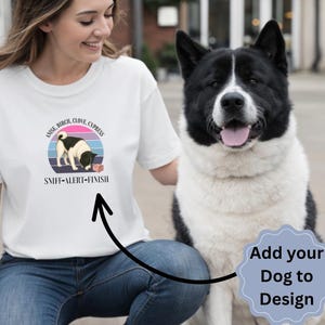 以下が含まれることがあります： 小さな箱の匂いを嗅ぐ犬のグラフィックが描かれた白い半袖Tシャツ。「ANISE, BIRCH, CLOVE, CYPRESS」および「SNIFF-ALERT-FINISH」という文字がプリントされています。青いタグには「MADE TO ORDER」と「Add your Dog to Design」と書かれています。