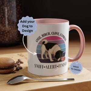 May include: A white ceramic mug with a light pink interior and handle. The front features a graphic of a dog with the text "ANISE, BIRCH, CLOVE, CYPRESS" and "SNIFF-ALERT-FINISH". A light blue starburst shape contains the text "Add your Dog to Design".