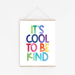 May include: A framed print with the text "It's Cool To Be Kind" in rainbow colors. The letters are stylized with a watercolor effect.