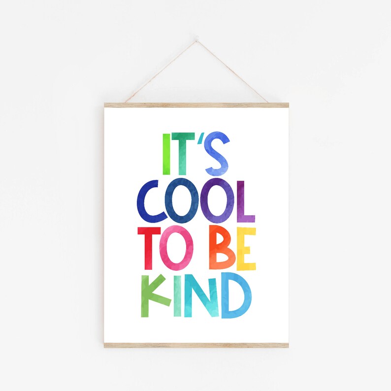 May include: A framed print with the text "It's Cool To Be Kind" in rainbow colors. The letters are stylized with a watercolor effect.