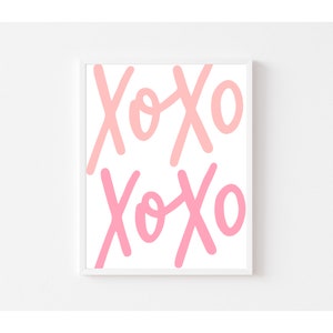 K&ouml;nnte beinhalten: Ein wei&szlig;er gerahmter Druck mit dem Wort "XOXO", das zweimal in Rosa und Hellrosa wiederholt wird.