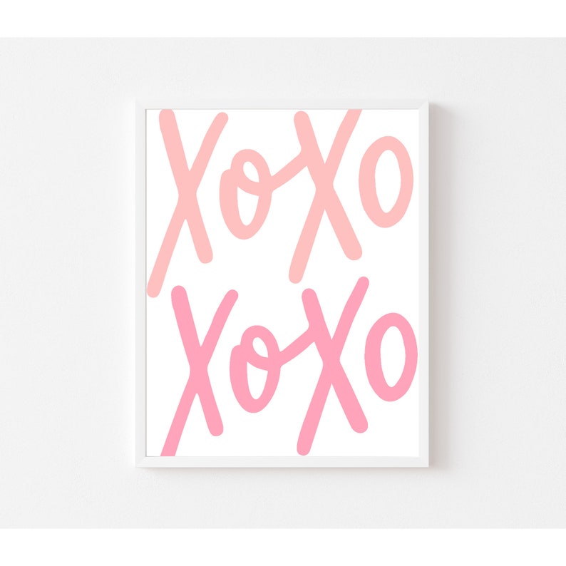 K&ouml;nnte beinhalten: Ein wei&szlig;er gerahmter Druck mit dem Wort "XOXO", das zweimal in Rosa und Hellrosa wiederholt wird.