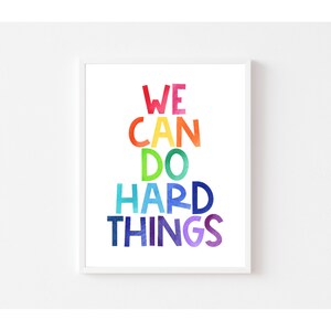 May include: A motivational poster with the text "WE CAN DO HARD THINGS" in rainbow colors. The words are stacked on top of each other, with each word in a different color of the rainbow.