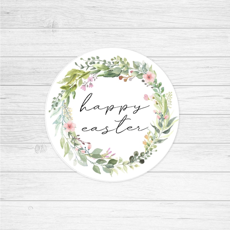 May include: A white circle with a green and pink floral wreath around the edge. The text "happy easter" is written in black script inside the wreath.