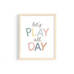 May include: A framed print with the text "let's PLAY all DAY" in colorful letters. The letters are in shades of green, yellow, blue, pink, and orange.