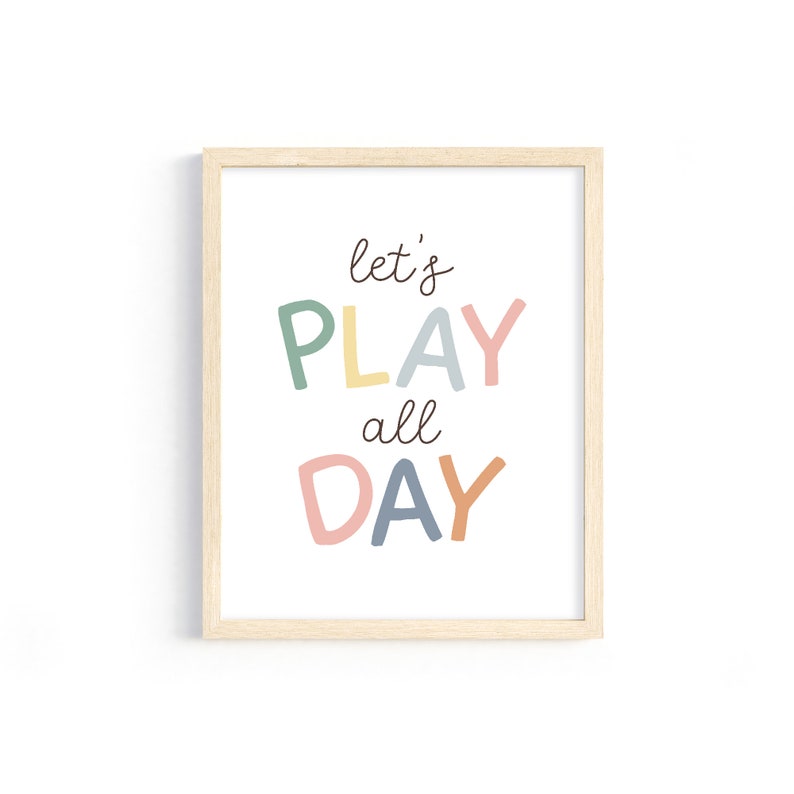May include: A framed print with the text "let's PLAY all DAY" in colorful letters. The letters are in shades of green, yellow, blue, pink, and orange.