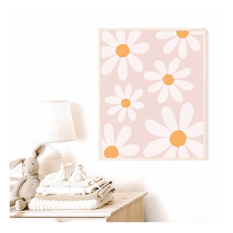 May include: A framed print with a pink background and a pattern of white daisies with orange centers.