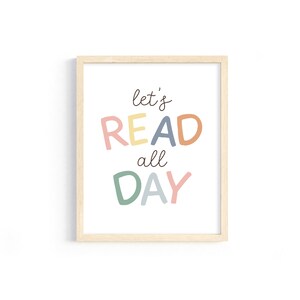 May include: A framed print with the text "let's READ all DAY" in colorful letters. The letters are in shades of pink, yellow, orange, blue, and green.