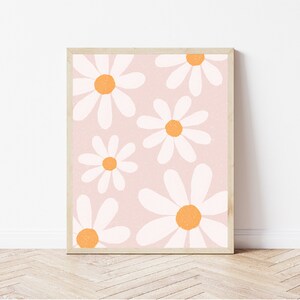 May include: A framed print with a pink background and a pattern of white daisies with orange centers.