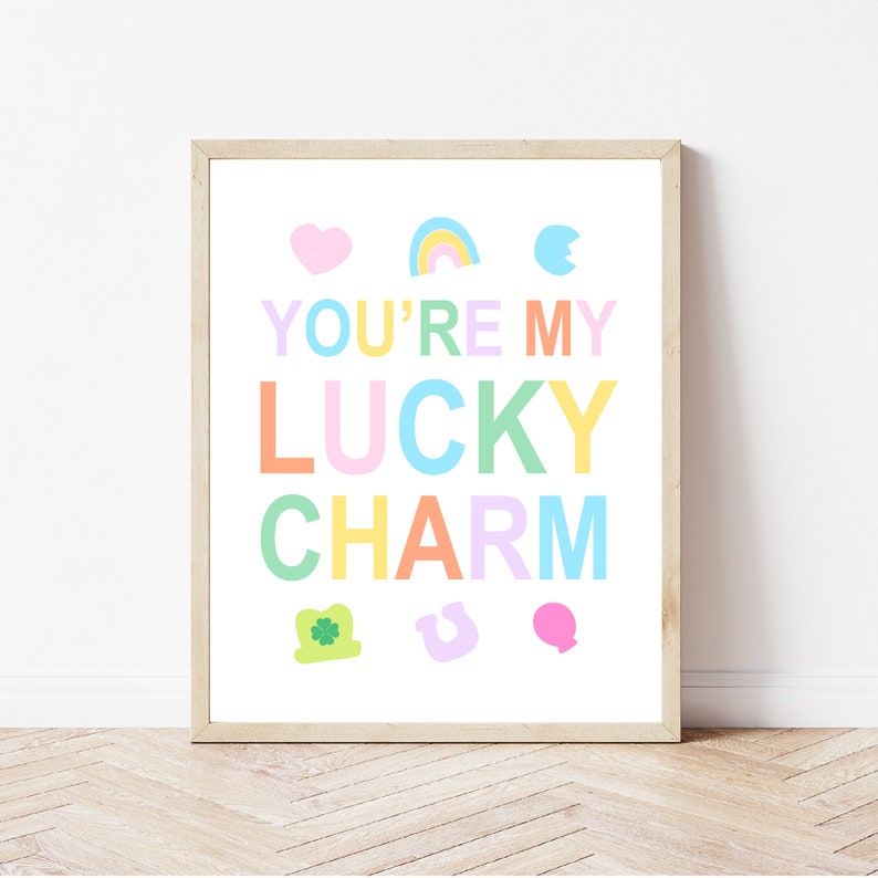 K&ouml;nnte beinhalten: Ein gerahmter Druck mit dem Text "You're my lucky charm" in Regenbogenfarben. Der Druck zeigt verschiedene Gl&uuml;cksbringer, darunter ein Herz, einen Regenbogen, ein Hufeisen, ein vierbl&auml;ttriges Kleeblatt und ein Kleeblatt.