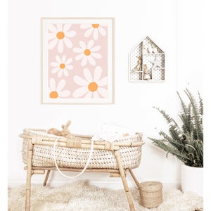 May include: A white wicker bassinet with a white blanket and a stuffed bunny inside. The bassinet is on a white rug in front of a white wall with a framed print of orange and white daisies and a white shelf with a house-shaped design.