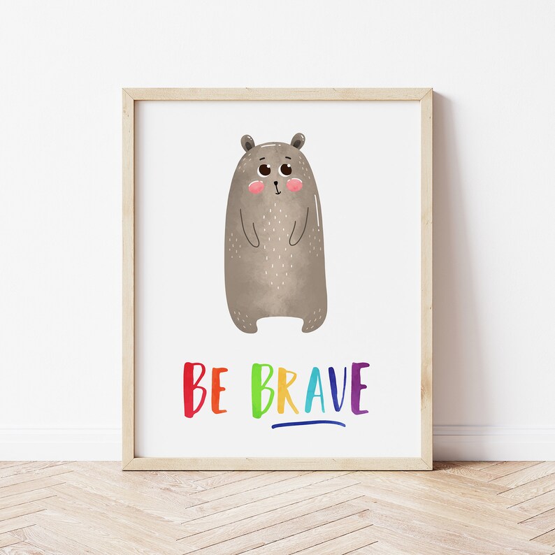 May include: A framed print with a cute cartoon brown bear and the text "BE BRAVE" in rainbow colors.