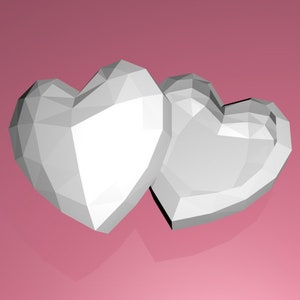 Peut inclure: Deux objets en forme de cœur géométriques blancs sur un fond rose.