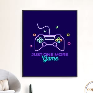 Op de afbeelding: Een ingelijste wandkunstprint met een neon-stijl videogamecontroller-ontwerp in paars, roze en oranje op een donkerblauwe achtergrond. De tekst "JUST ONE MORE Game" staat eronder. Modern gaming thema.