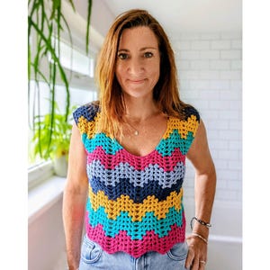 Puede incluir: Top de ganchillo hecho a mano con cuello en V. El top presenta un patrón de chevron en tonos rosa, azul, amarillo y turquesa. Este top sin mangas es una prenda vibrante y llamativa.