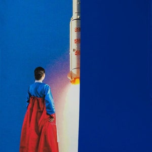 May include: A woman in a red and blue traditional Korean dress stands facing a large white rocket with a red flag on the side. The rocket is launching with a bright white plume of smoke.