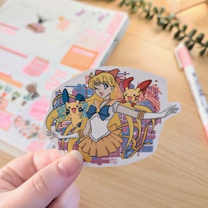 May include: A sticker featuring a cartoon character with yellow hair, a blue sailor outfit, and a yellow skirt. The character is holding two small yellow cartoon creatures. The sticker has a colorful background with a pixelated design.