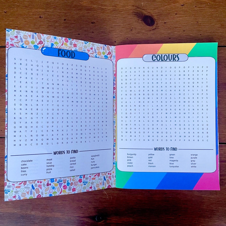 May include: A colorful word search puzzle book with two pages. The left page has a food theme and the right page has a colors theme. The words to find are listed below each puzzle.