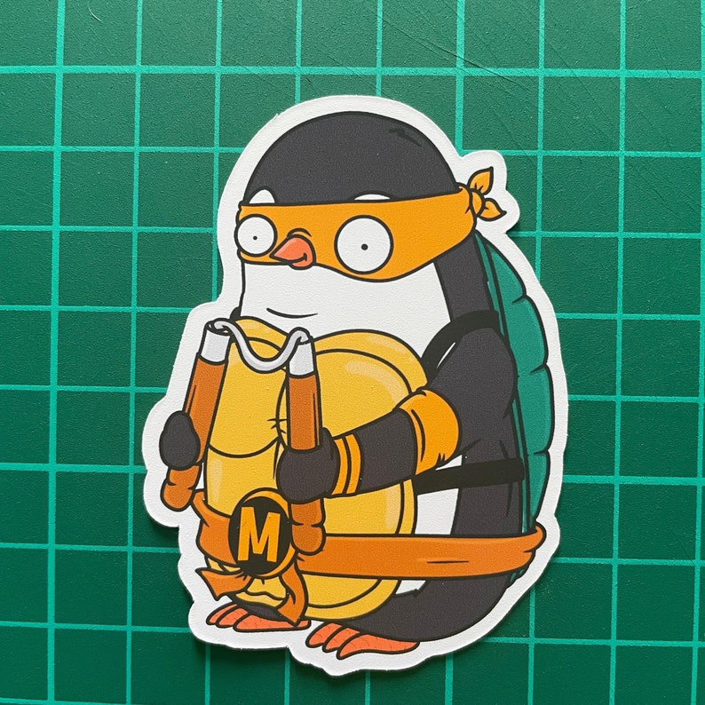 Puede incluir: Un ping&uuml;ino de dibujos animados vestido con un disfraz de tortuga ninja negro y naranja, sosteniendo un par de nunchakus. El ping&uuml;ino lleva una concha verde y tiene una bandana amarilla alrededor de la cabeza. El ping&uuml;ino est&aacute; de pie sobre un fondo blanco.